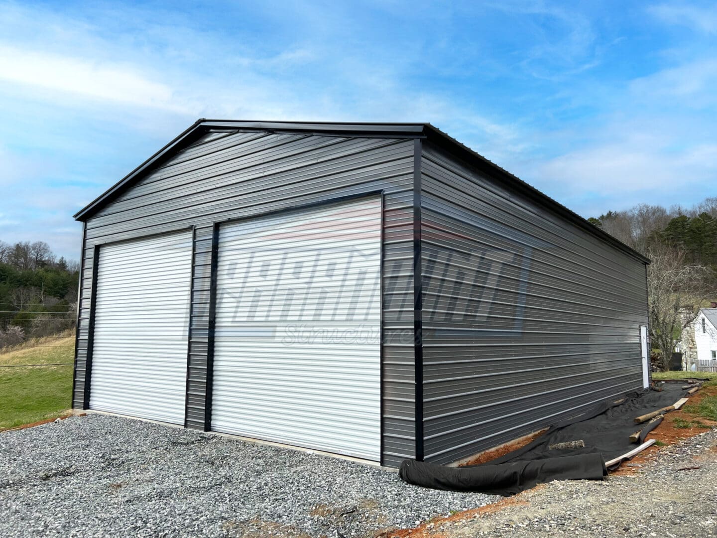 A large metal garage with two doors and a roll up door.