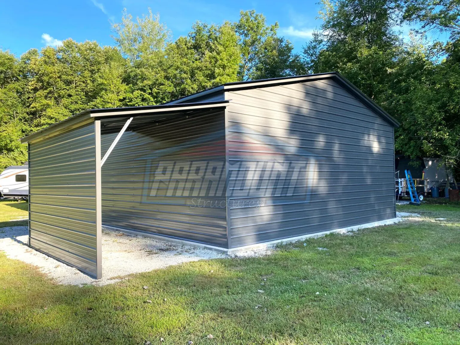 A gray metal garage with a black roof.