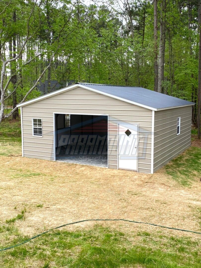 A garage with a door open in the middle of a field.