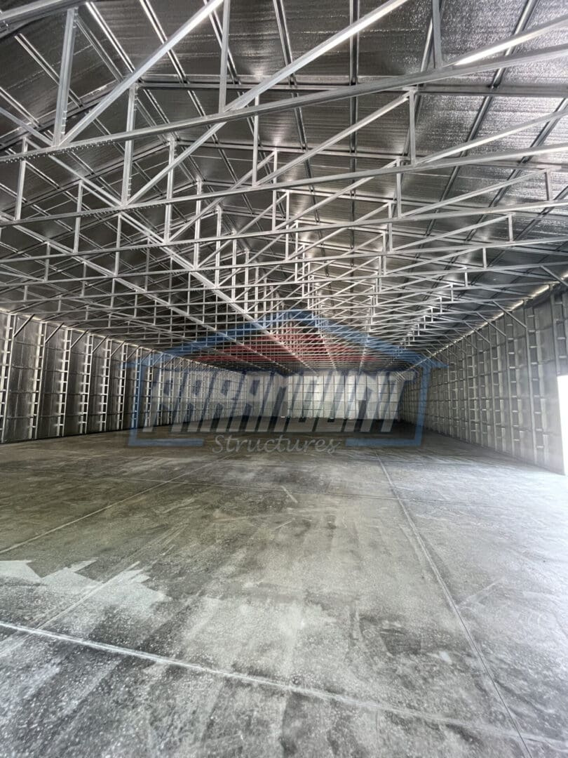 A large empty warehouse with metal beams on the ceiling.