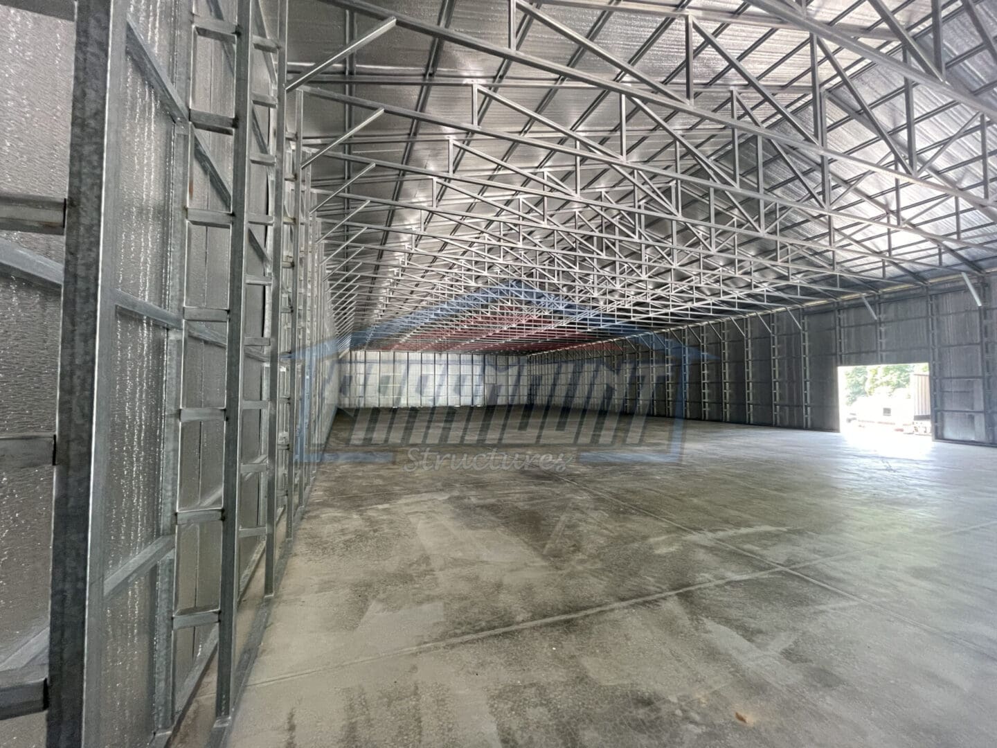 A large warehouse with metal roof and concrete floor.