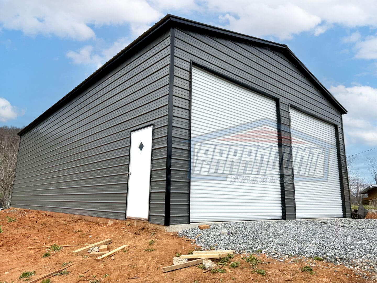 A large metal building with two doors and a garage door.