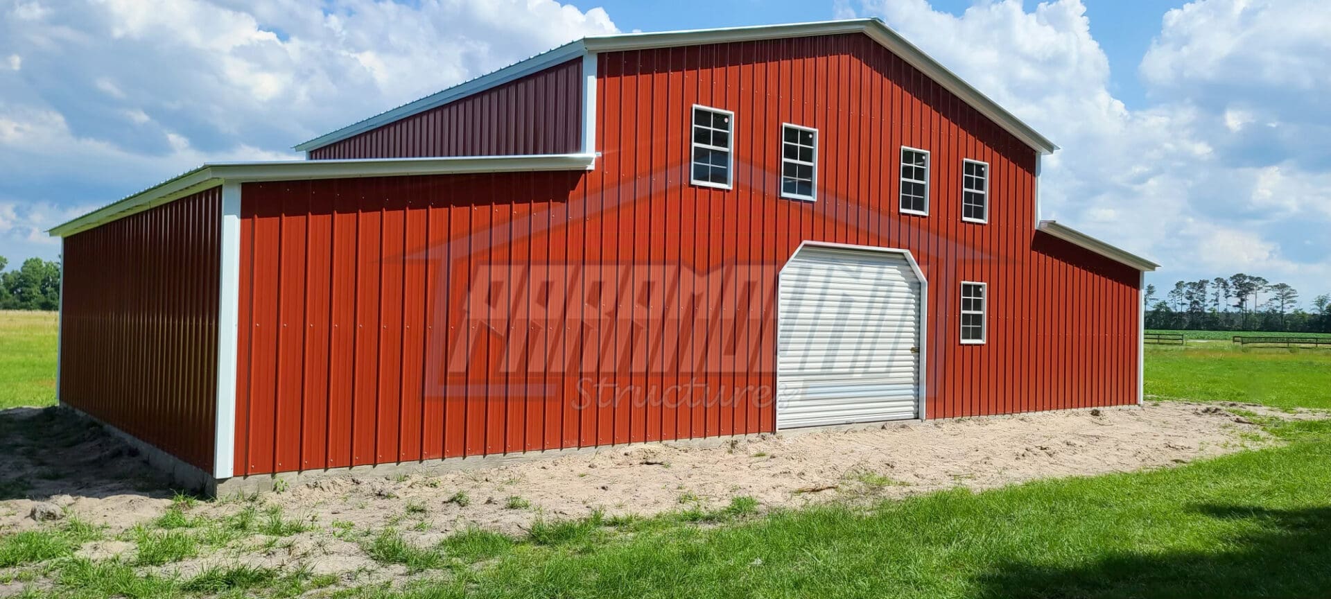 A red barn with two windows and a white door.