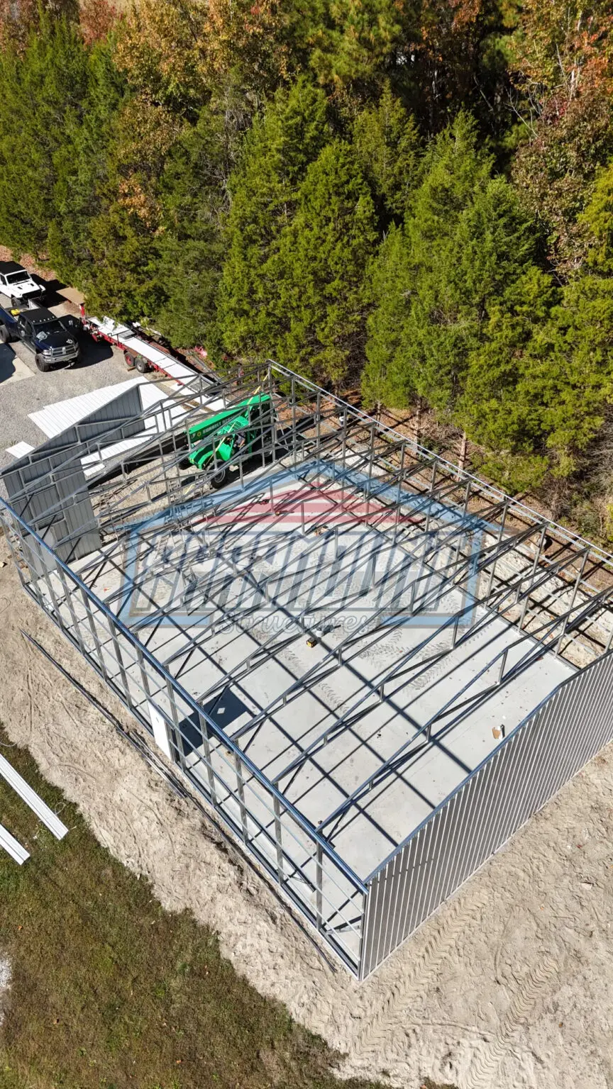 An aerial view of a steel building in a wooded area.