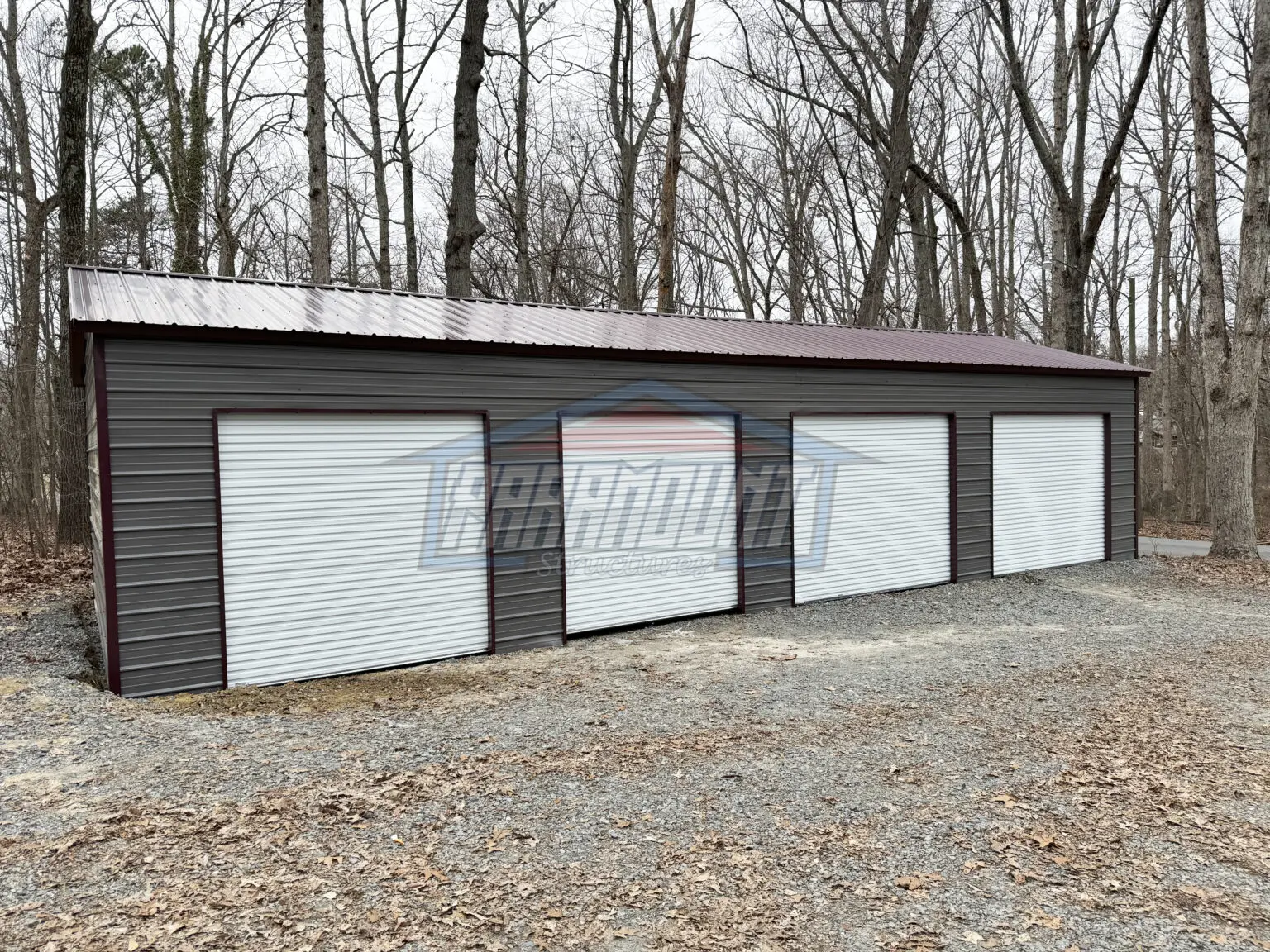 A photo of a four-car steel garage with white roll-up doors.