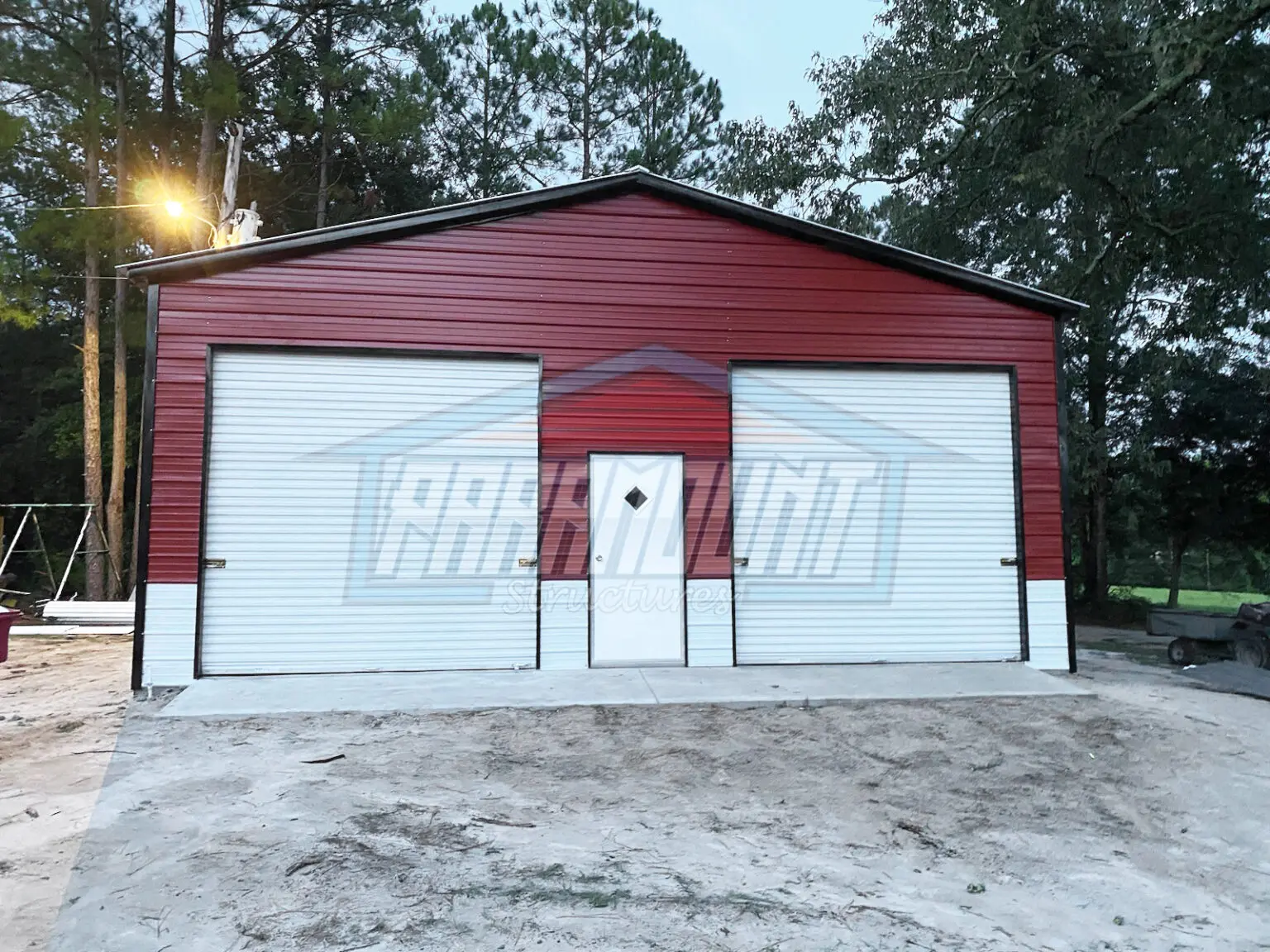 A metal building with two garage doors and a single door.