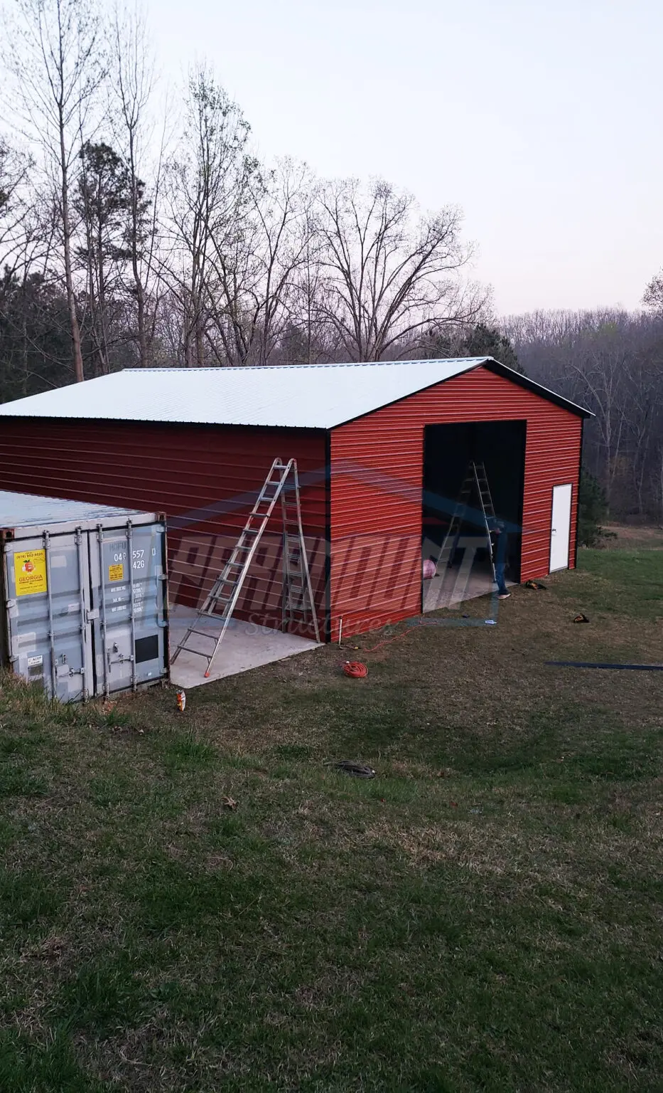 Red metal barn with white trim and open garage door.