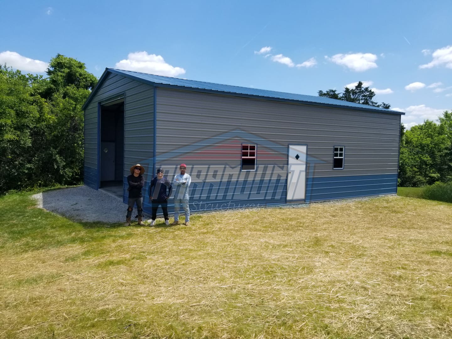 Grey metal garage with three men standing.