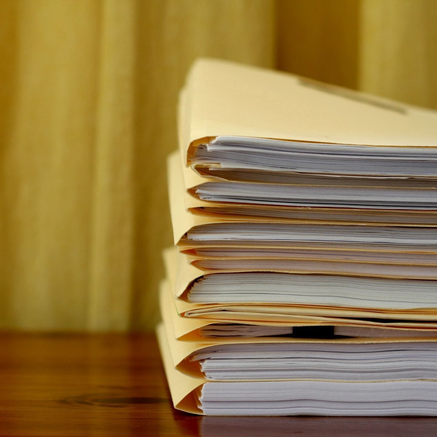 A stack of papers sitting on top of a wooden table.